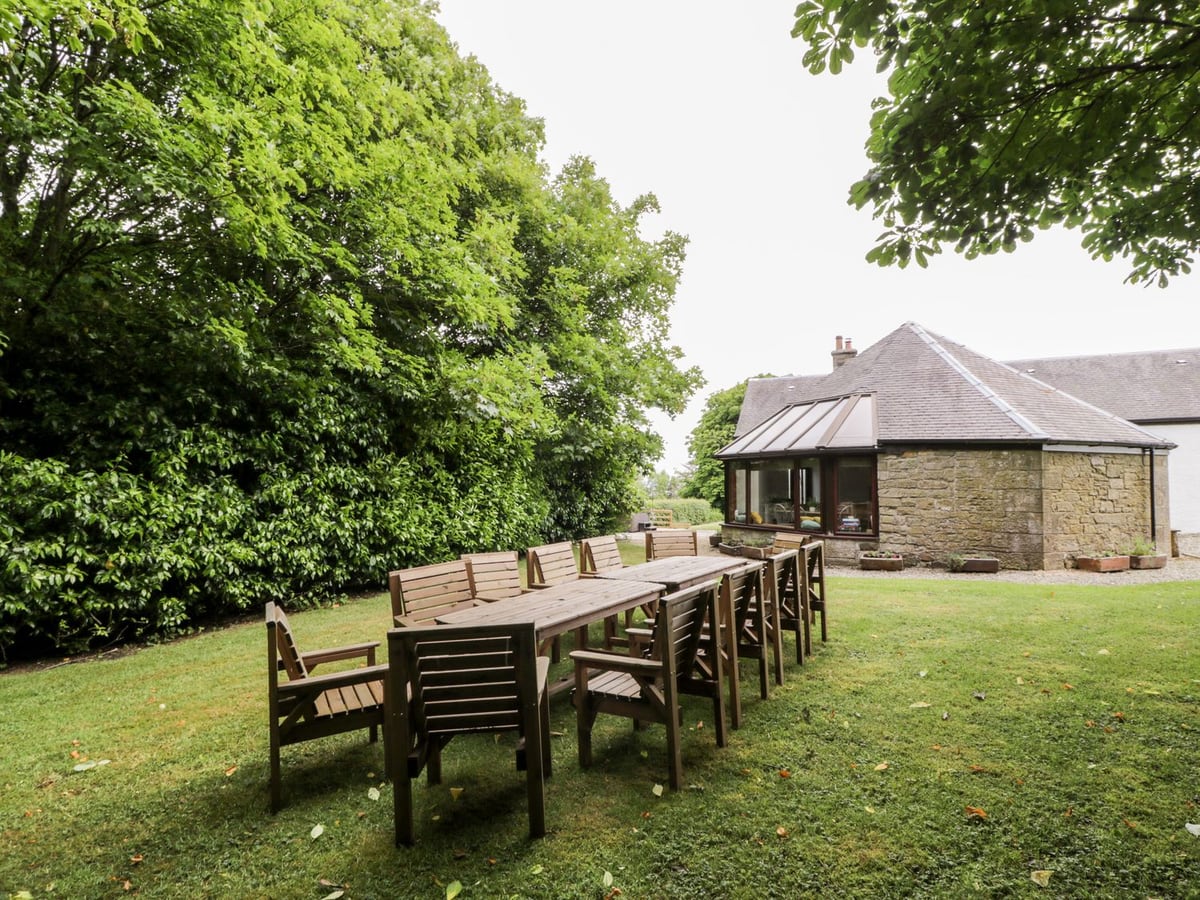 Outdoor dining tables on the lawn beside the stone sunroom at Shieldhill Farm House