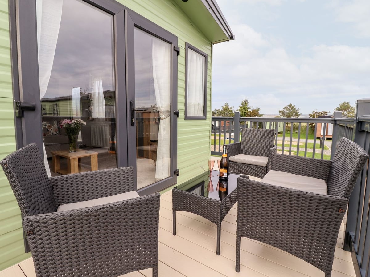 Outdoor chairs and a glass table on the deck beside the patio doors at Silverdale View