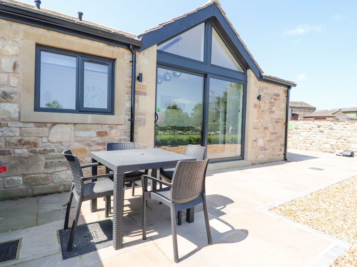 Skirden View stone exterior with gabled glass doors and a dining table on the patio