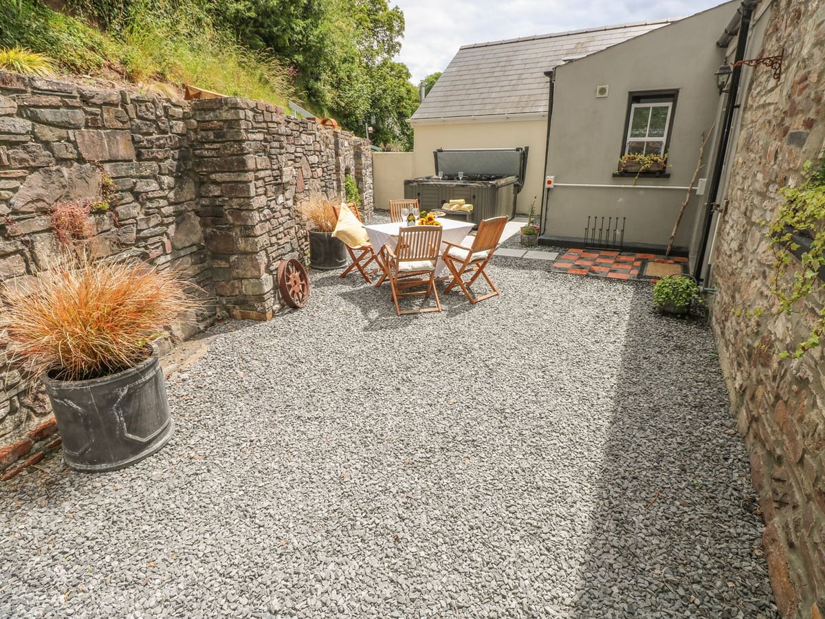 Snowdrop Cottage gravel courtyard with stone walls, table and chairs and a hot tub at the far end