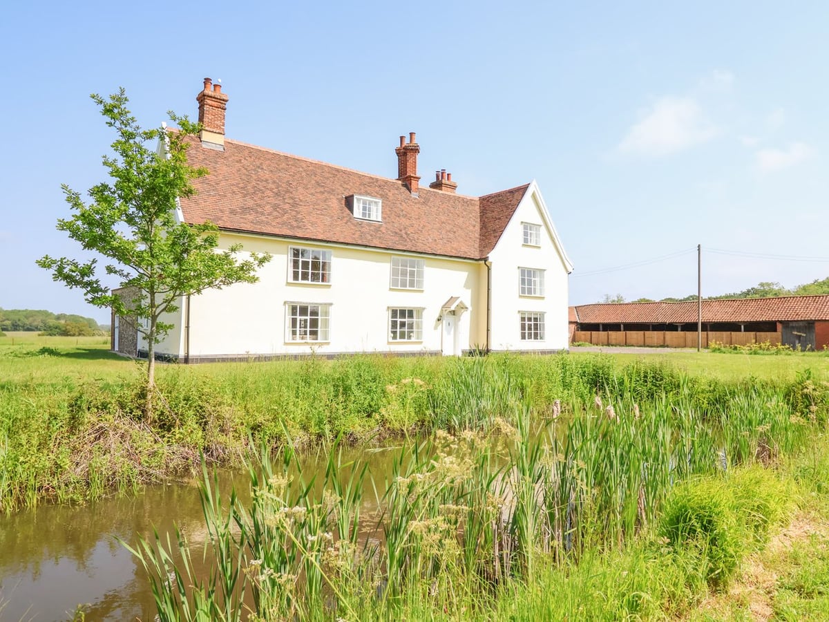 South Grange House across a pond with lawns and Suffolk countryside