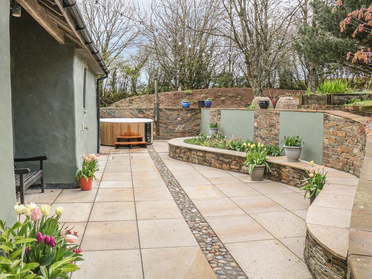 Spring Park Farmhouse patio with a wood-clad hot tub, stone planters and pots of flowers