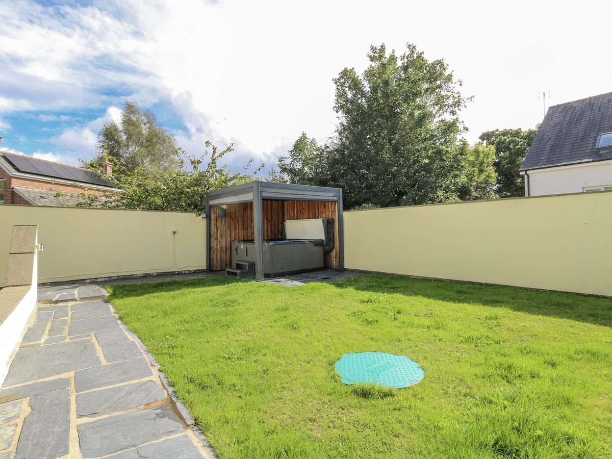 Station Hall walled lawn with slate path and a hot tub under a roofed wooden shelter