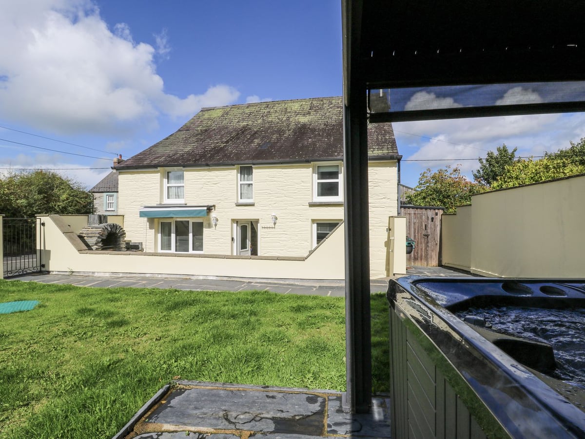 Station Hall seen across the rear lawn, with a sheltered hot tub at the garden edge