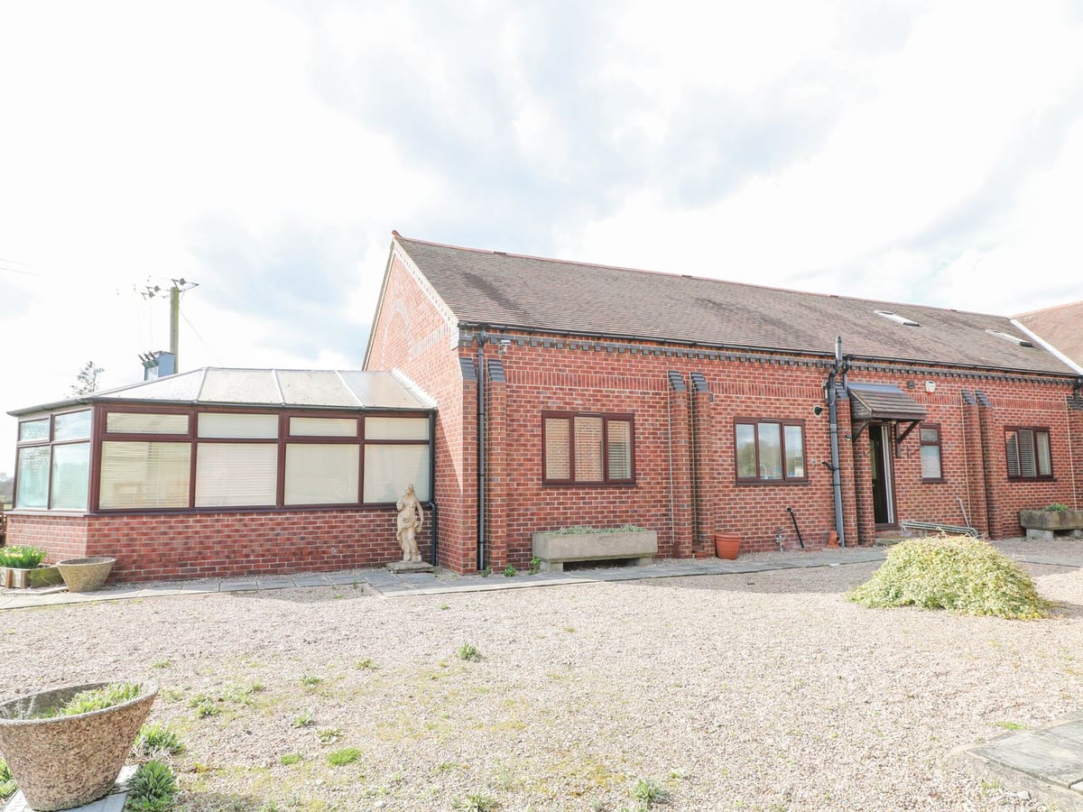 Red brick Stensonhill Lodge with a glazed conservatory and a broad gravel approach