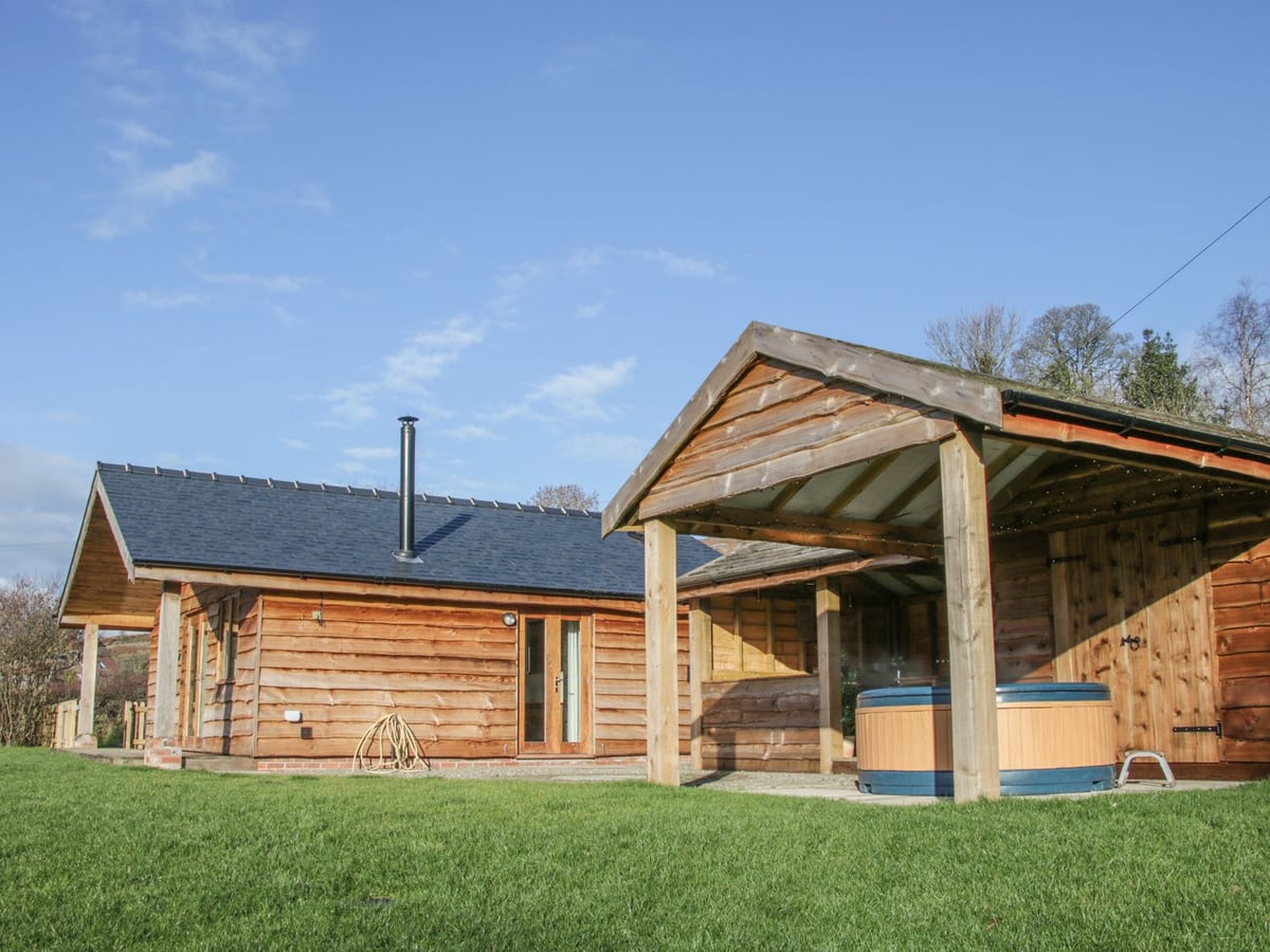 Stoney-Brook Lodge with lawn in front and a round hot tub beneath its timber roof