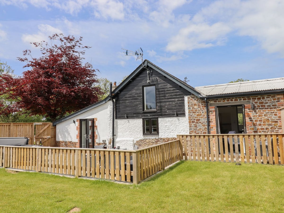 Black gable and white walls behind a timber-railed patio at Strawberry Bank Kingfisher