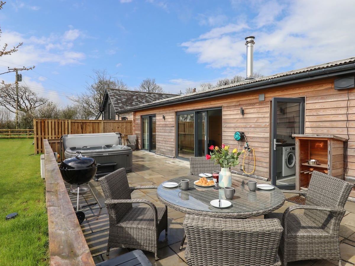 Timber-clad Strawberry Bank Nuthatch beside its paved terrace, dining table and hot tub
