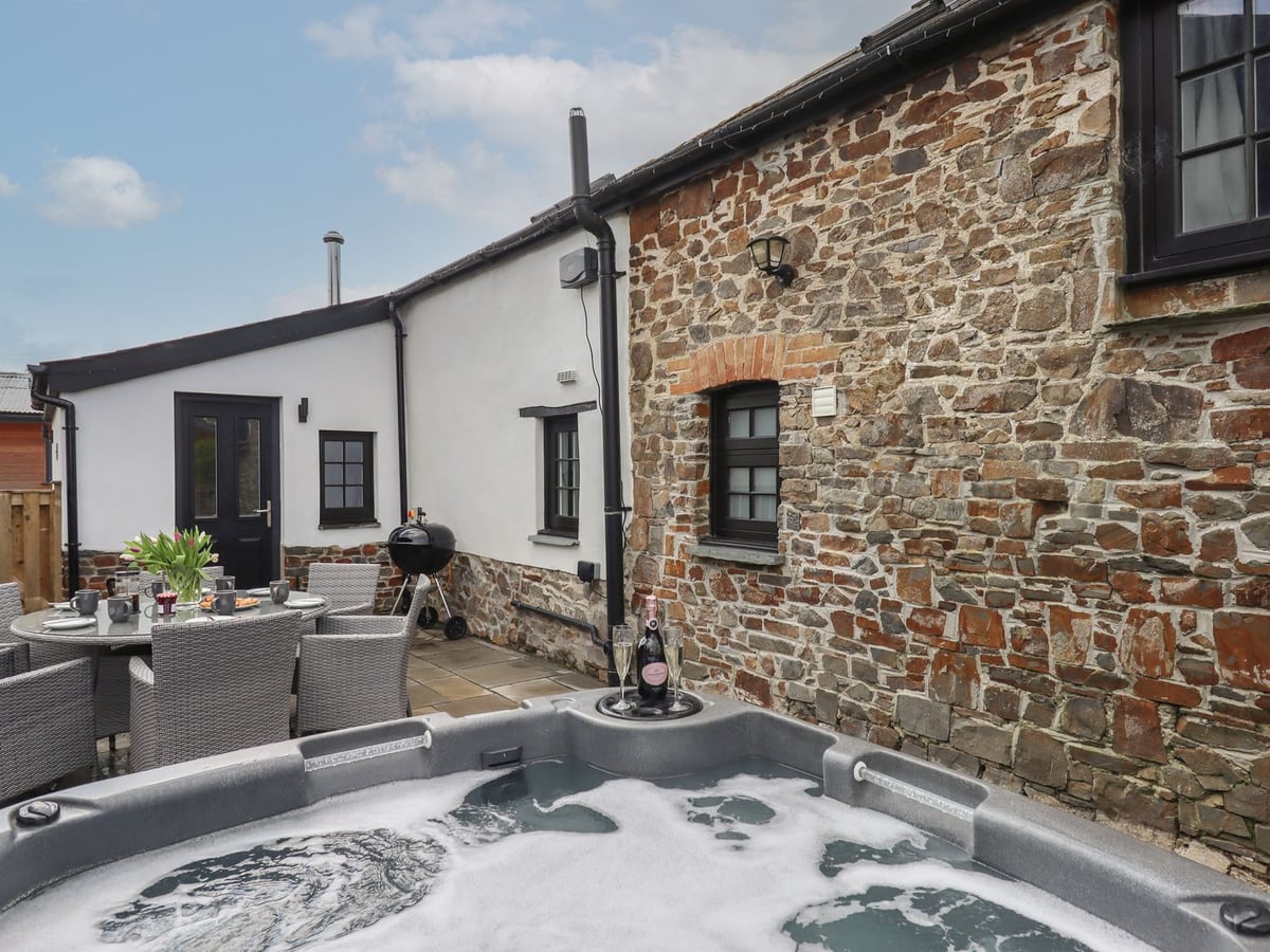 Stone and white walls beside the terrace seating and hot tub at Strawberry Bank Pipistrelle