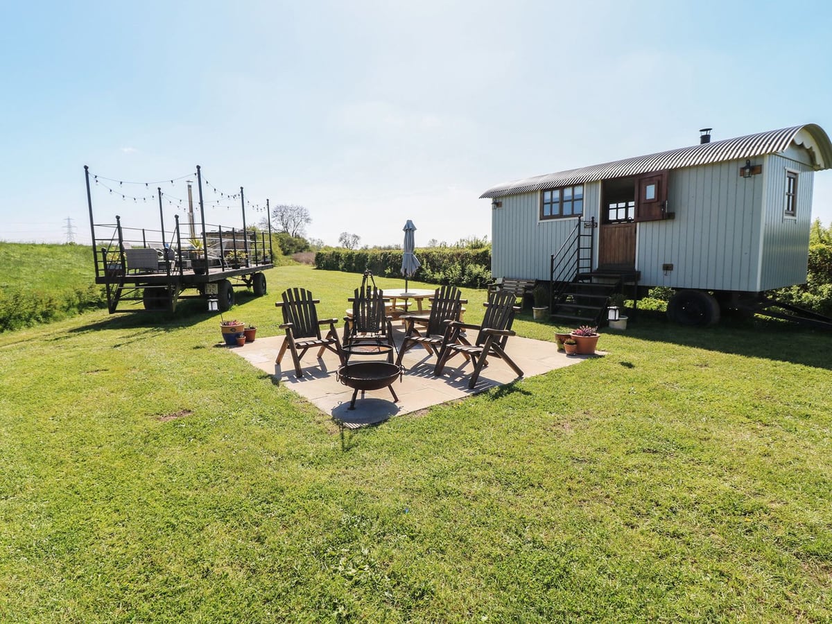 Sweet Caroline Shepherd's Hut with open lawn, patio chairs and a raised hot-tub terrace