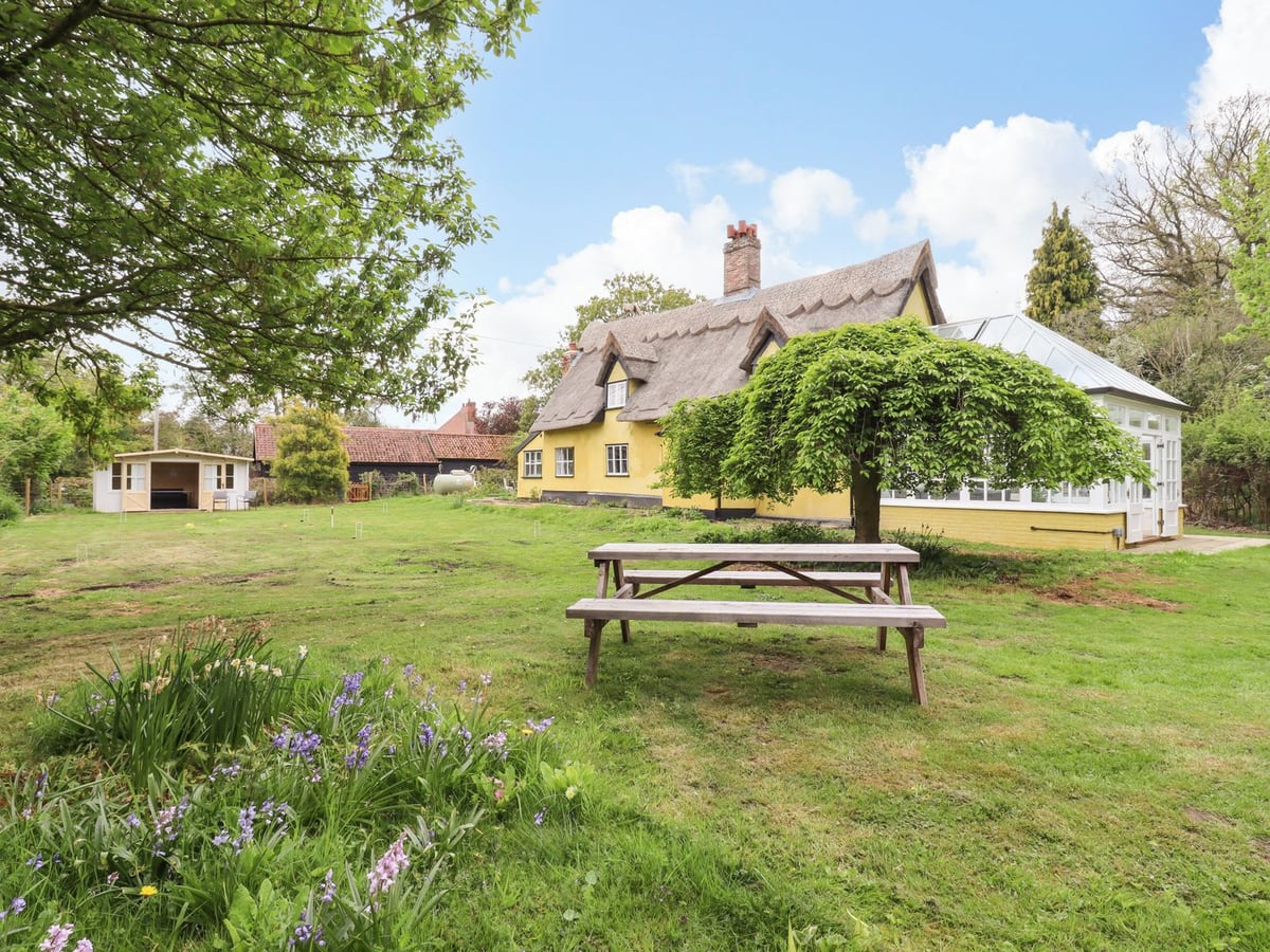 Thatched Abbey Cottage garden with picnic table and flowers