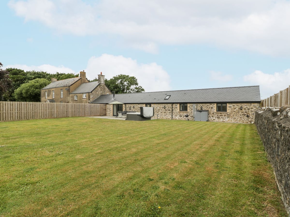 The Byre stone barn conversion with a large lawn, fenced and walled edges, patio and covered hot tub