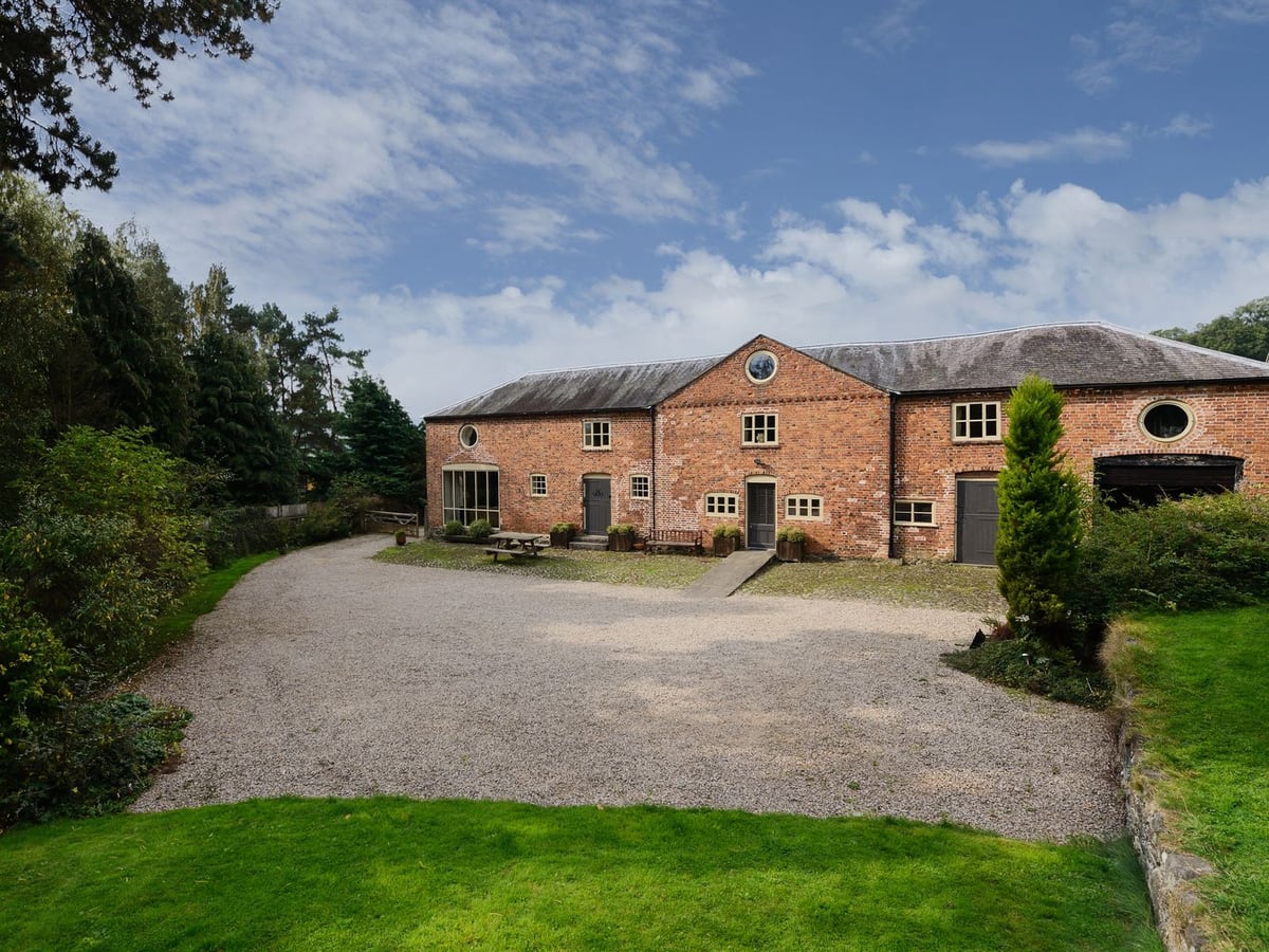 The Coach House's broad brick exterior facing a gravel drive and lawn edged by trees