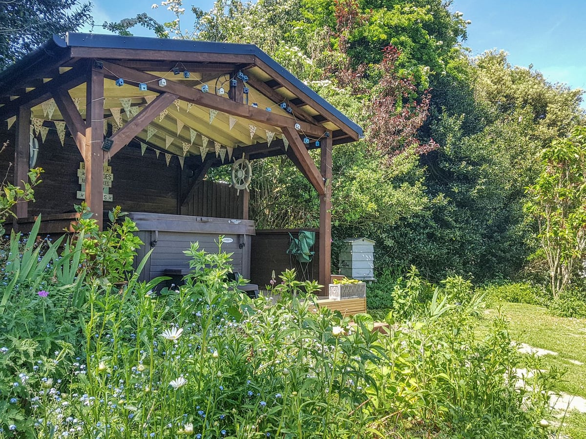 Covered hot tub beside the planted garden at The Coach House on the Isle of Wight