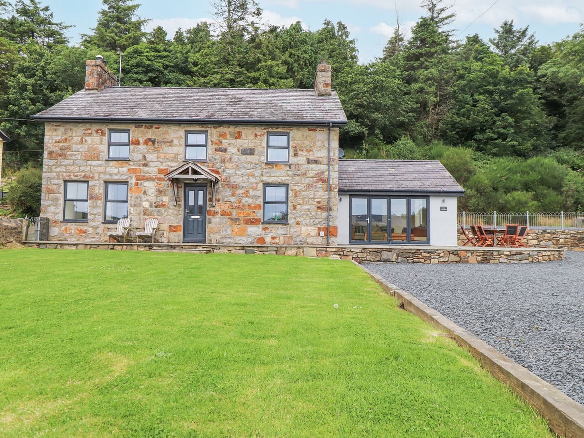 Stone-built The Cottage with a front lawn, gravel area and a raised patio with an outdoor dining set