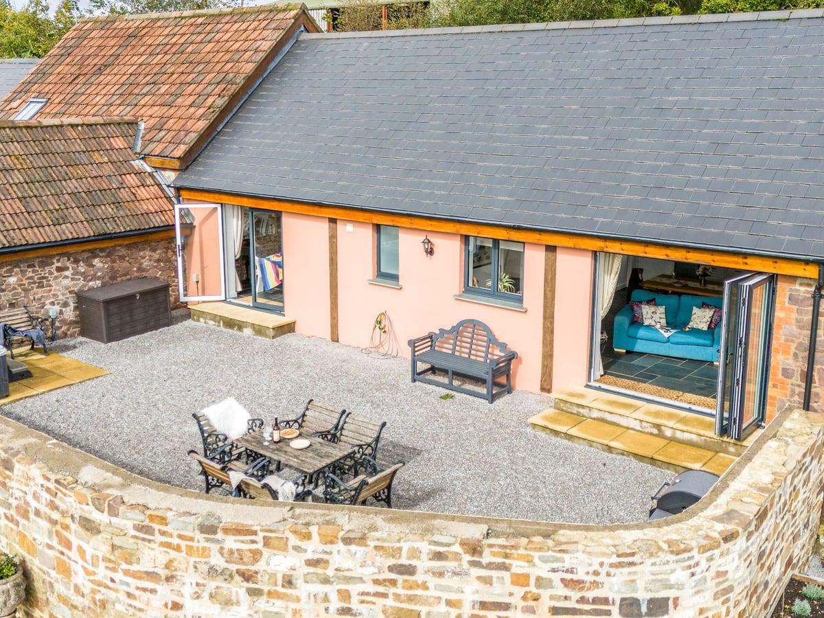 Pink cottage facade with open glazed doors facing a walled gravel courtyard at The Farm Office