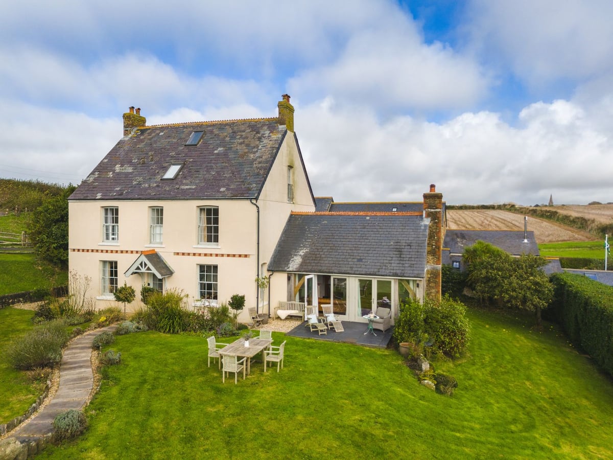 Farmhouse with a glazed garden room, outdoor table and lawns at The Farmhouse at Broad Downs