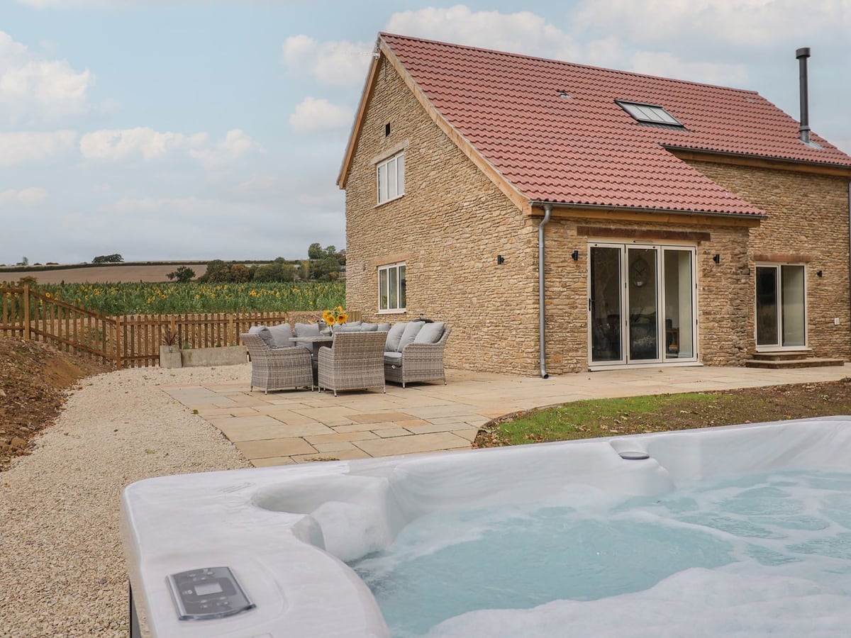 The Fox Den patio and hot tub beside the stone house and open countryside