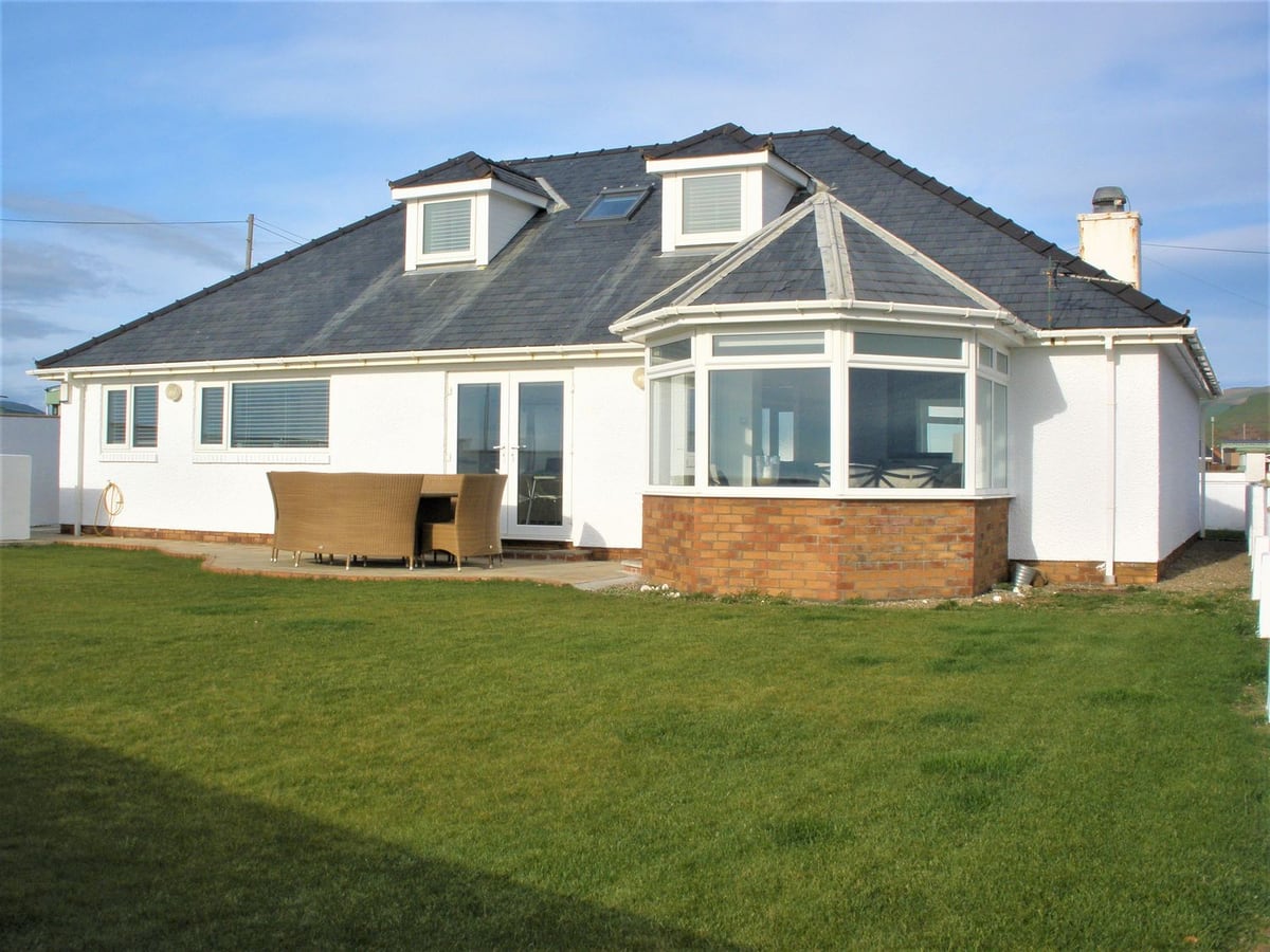 The Gables white house with a bay window, patio dining set and lawn