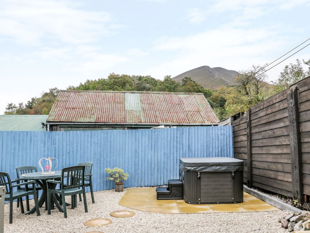 The Hayloft's gravel courtyard with table, chairs and a covered hot tub beside fencing