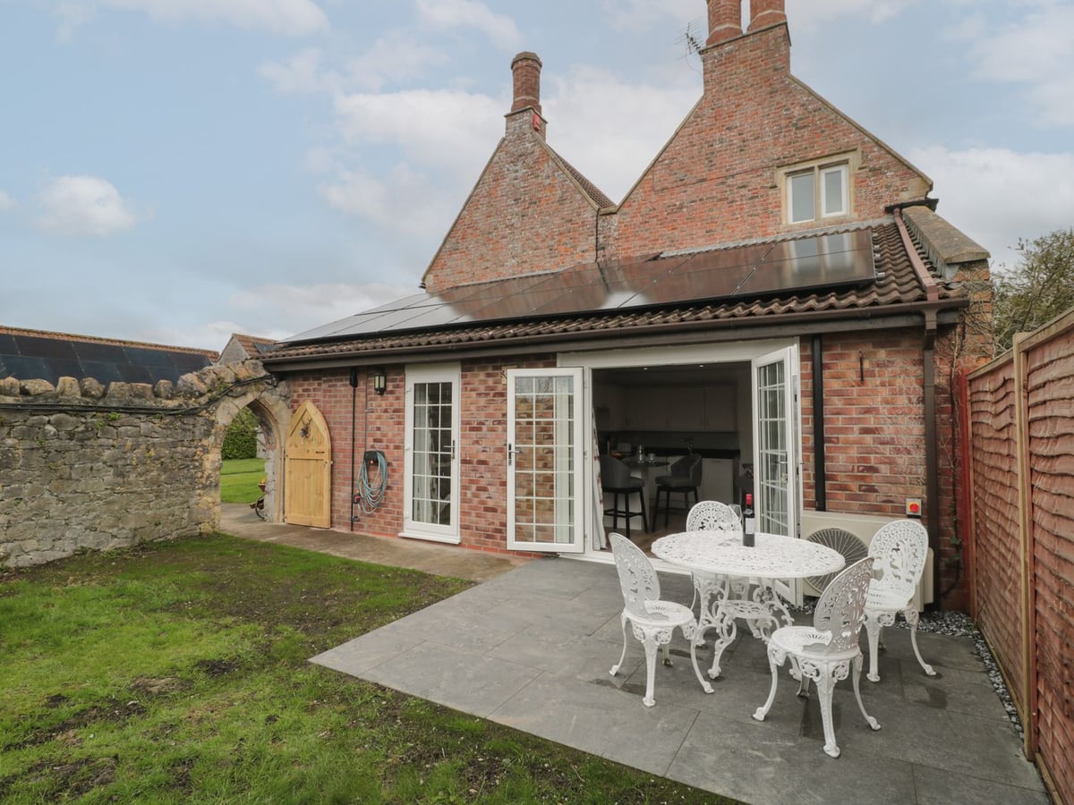 The Hideaway patio seating and lawn outside the brick cottage in Lympsham