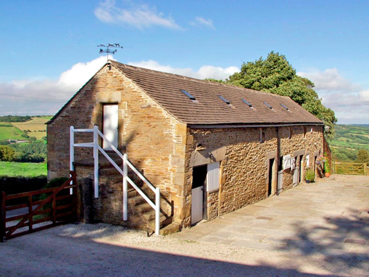 Stone barn exterior at The Loft with outside stairs, stable doors and a paved farm courtyard