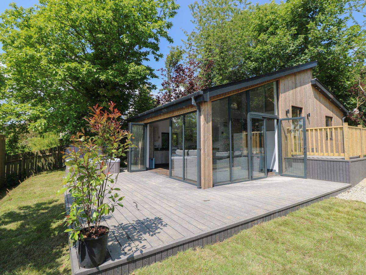 The Nest Brython with glass doors opening onto a timber deck beside grass and trees