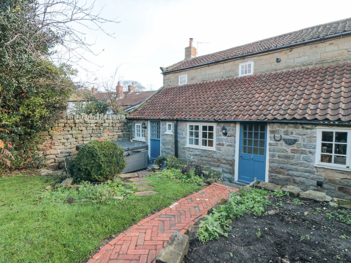 Stone rear exterior, blue doors and brick path through the garden at The Nook at 29 High Street