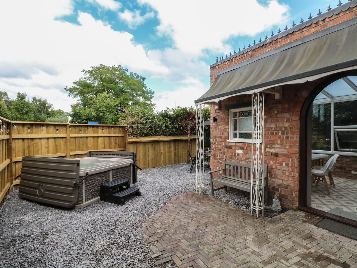 The Nook's brick entrance beside its gravel courtyard, hot tub and wooden fencing