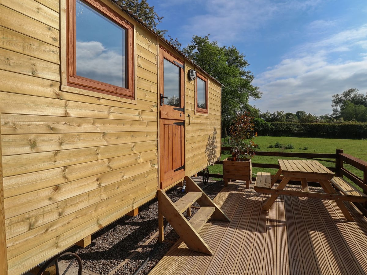 The Oak Hut's timber exterior beside a picnic table on decking, with grass beyond