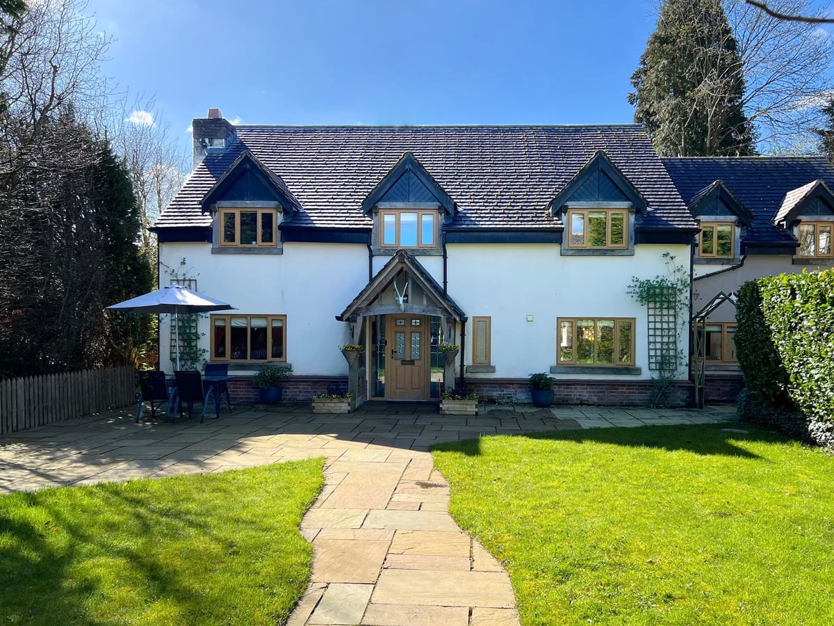 The Oaks house with a timber porch, lawn and paved path between planted garden edges