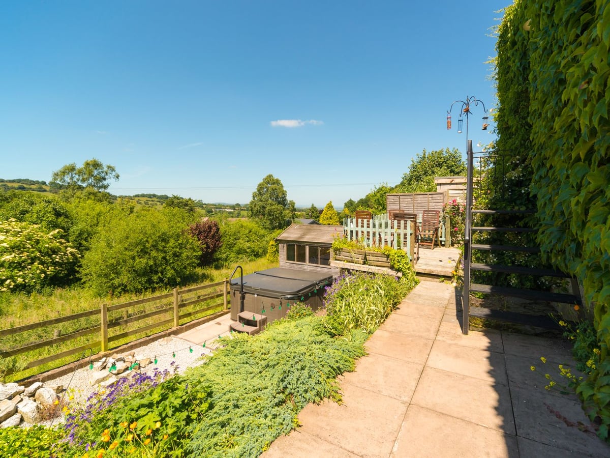 The Old Chapel's terraced garden with a covered hot tub, outdoor stairs and valley views