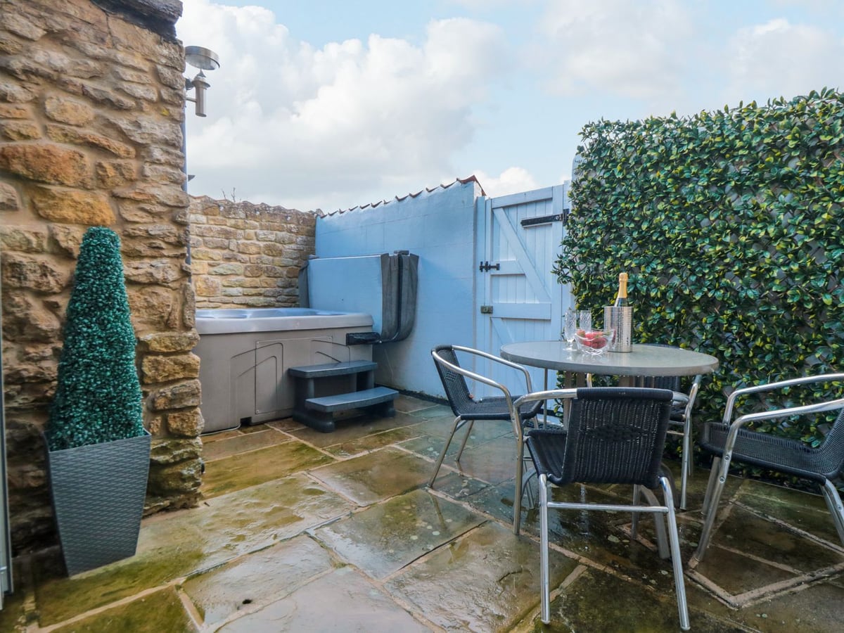 Small patio with hot tub, table and chairs outside The Old Chapel in Brompton
