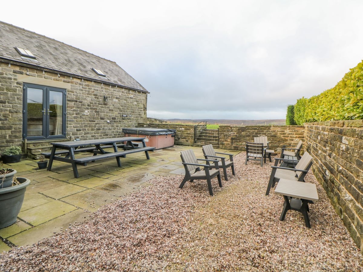 The Old Robin Hood patio with a covered hot tub, picnic table, chairs and stone boundary walls