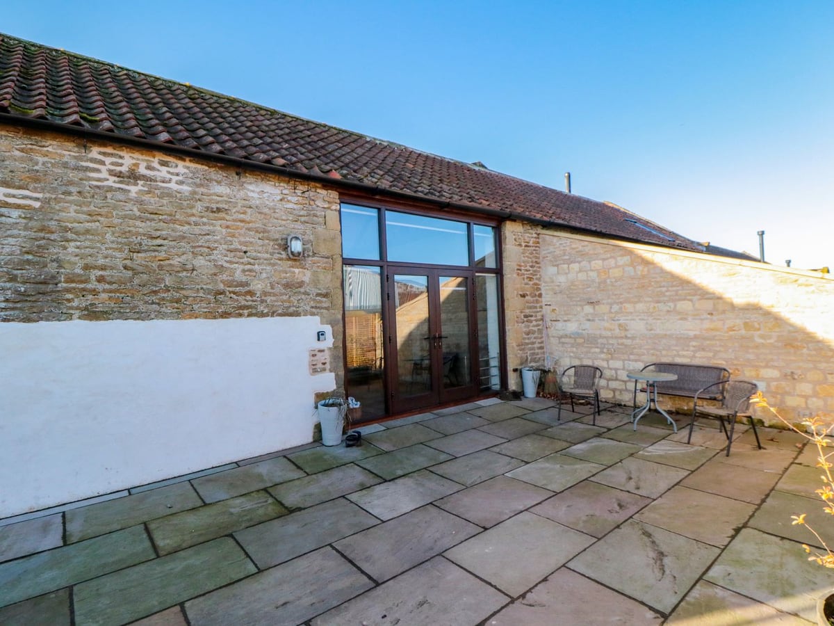 Stone exterior and paved courtyard with outdoor seating at The Old Workshop