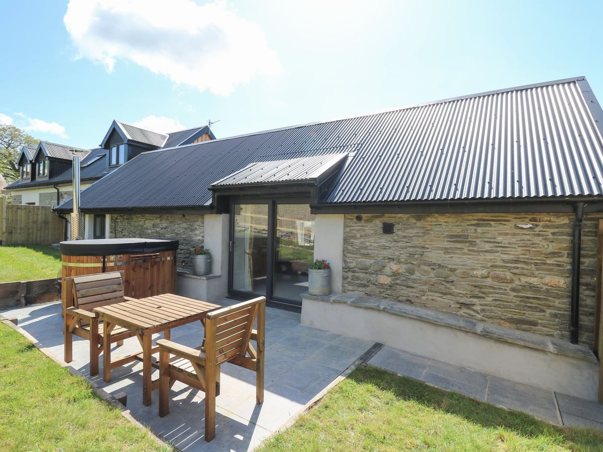 The Parlour stone barn with slate patio, wooden table, wood-fired hot tub and patio doors
