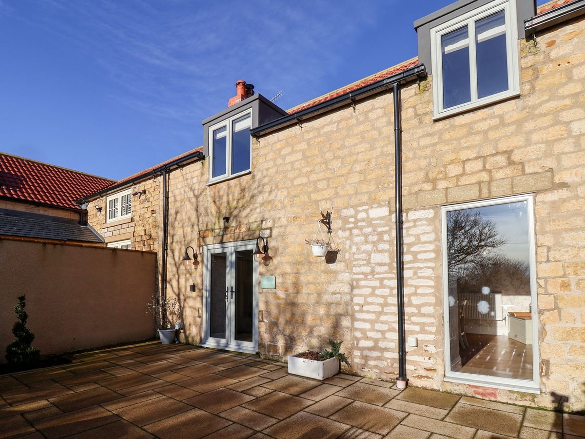 Stone patio and cottage exterior with glass doors at The Pheasantry