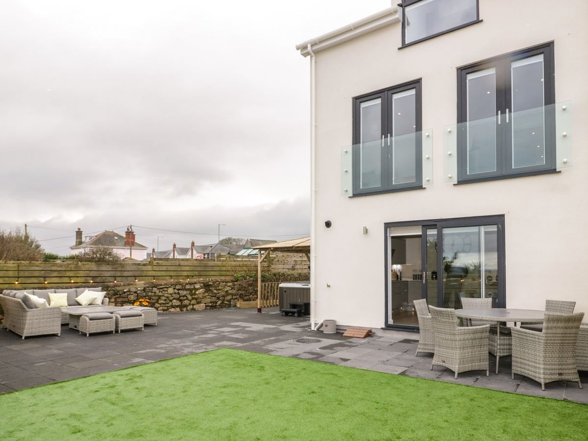 The Sandy Bee rear exterior with a green garden surface, paved patio and outdoor seating