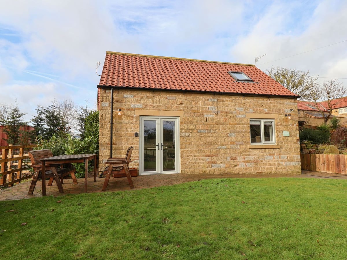 Stone cottage with grassy yard and picnic table outside The Stables near Seamer