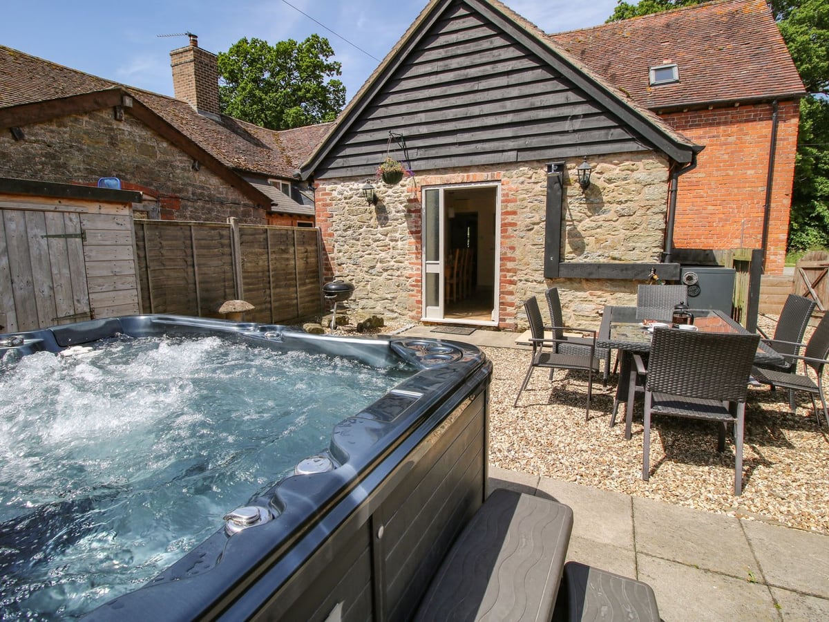 The Wain House's stone and timber gable facing a gravel courtyard with hot tub and seats