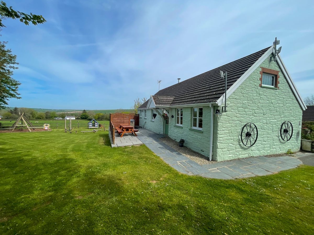 The Wheel @ Canllefaes bungalow with a screened patio, picnic bench and lawn by a play area