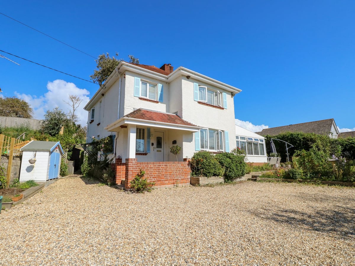 Topsails white house exterior with blue shutters and gravel driveway in Totland Bay