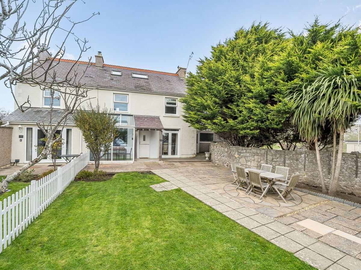 Ty Mawr, Great Orme lawn and paved patio with table and chairs beside a white picket fence