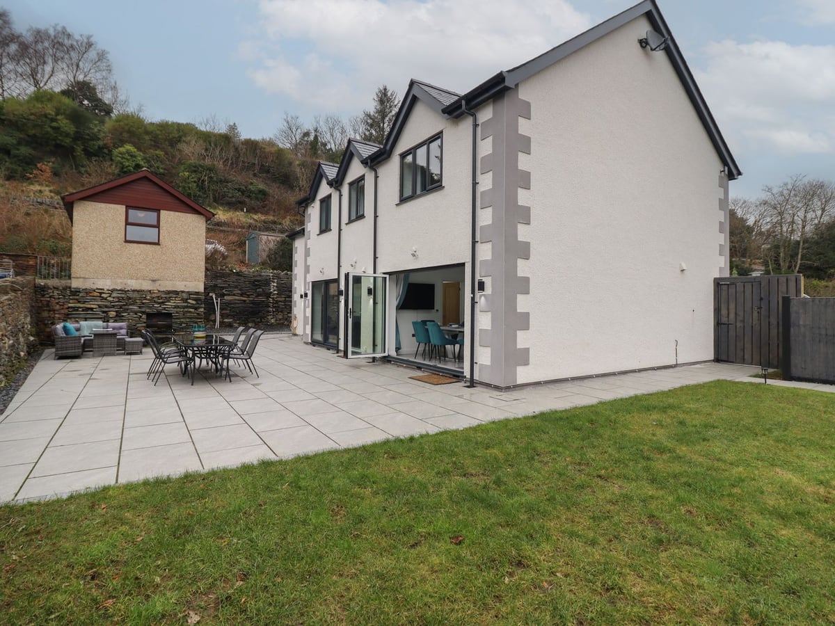 Ty Mawr rear patio with lawn, outdoor dining, seating, and house exterior