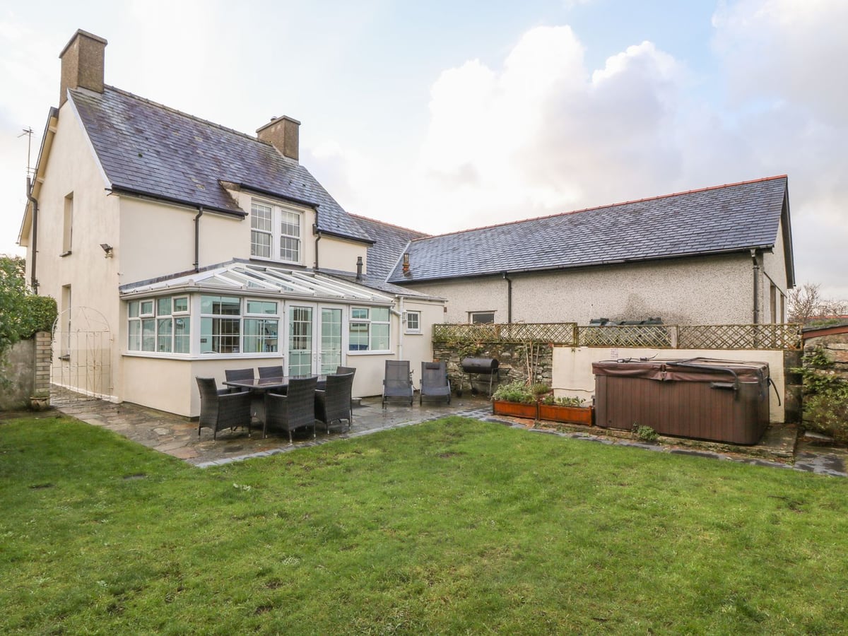 Ty'r Ysgol rear lawn with patio dining, barbecue, hot tub, and conservatory