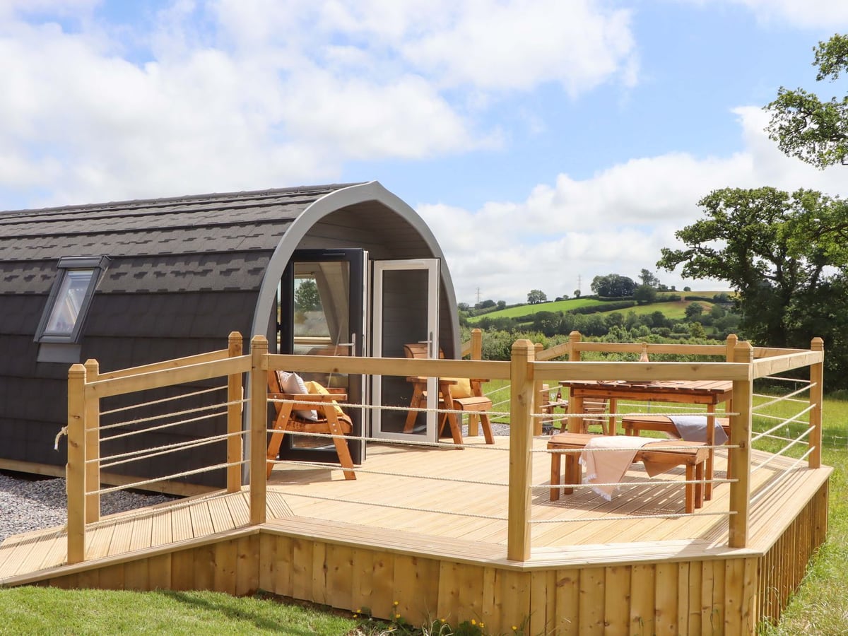 Curved roof and open doors above the timber deck and rope railings at Under Oak Pod
