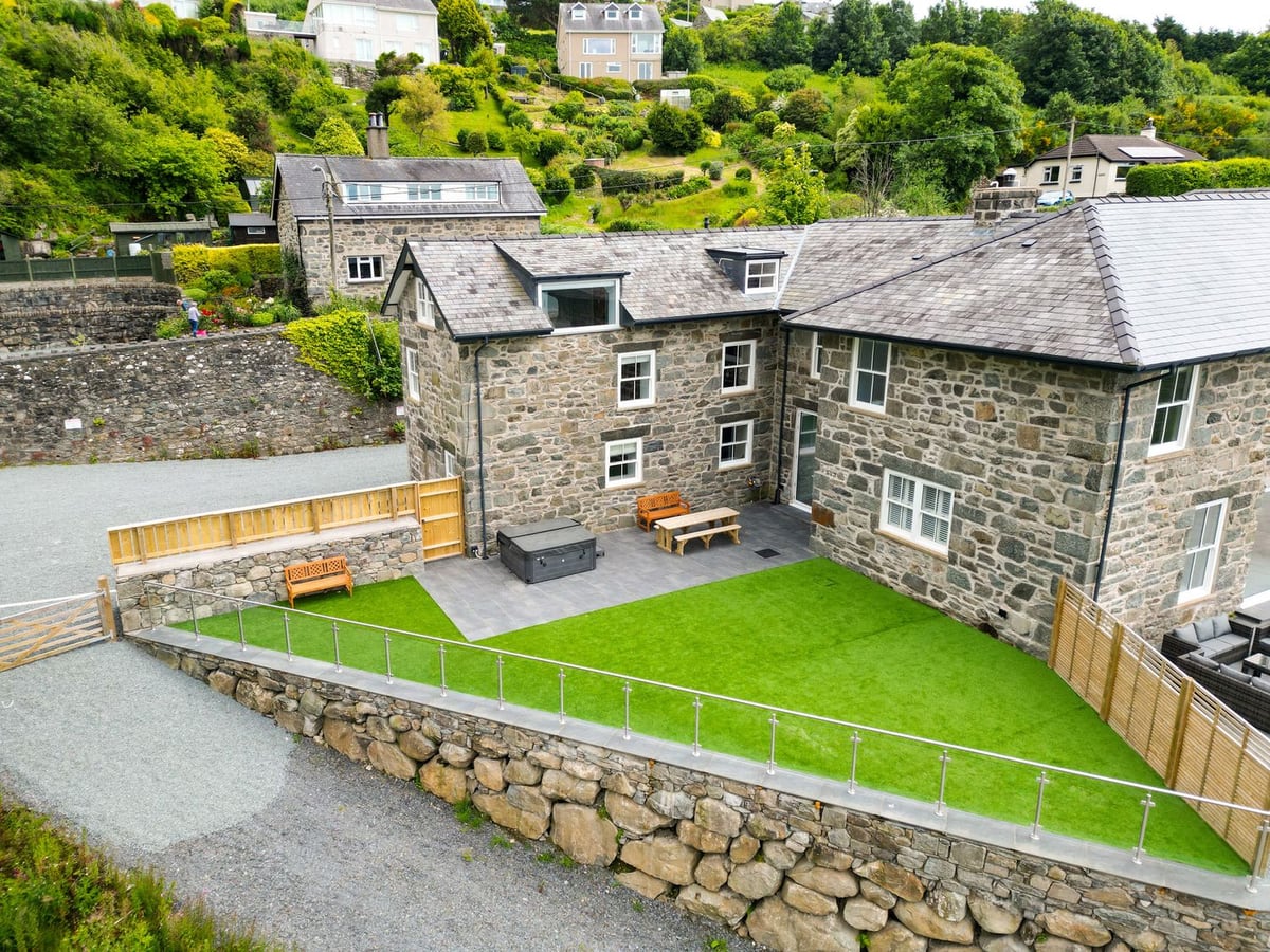 Valerian Lodge stone courtyard with artificial lawn, hot tub, and picnic bench