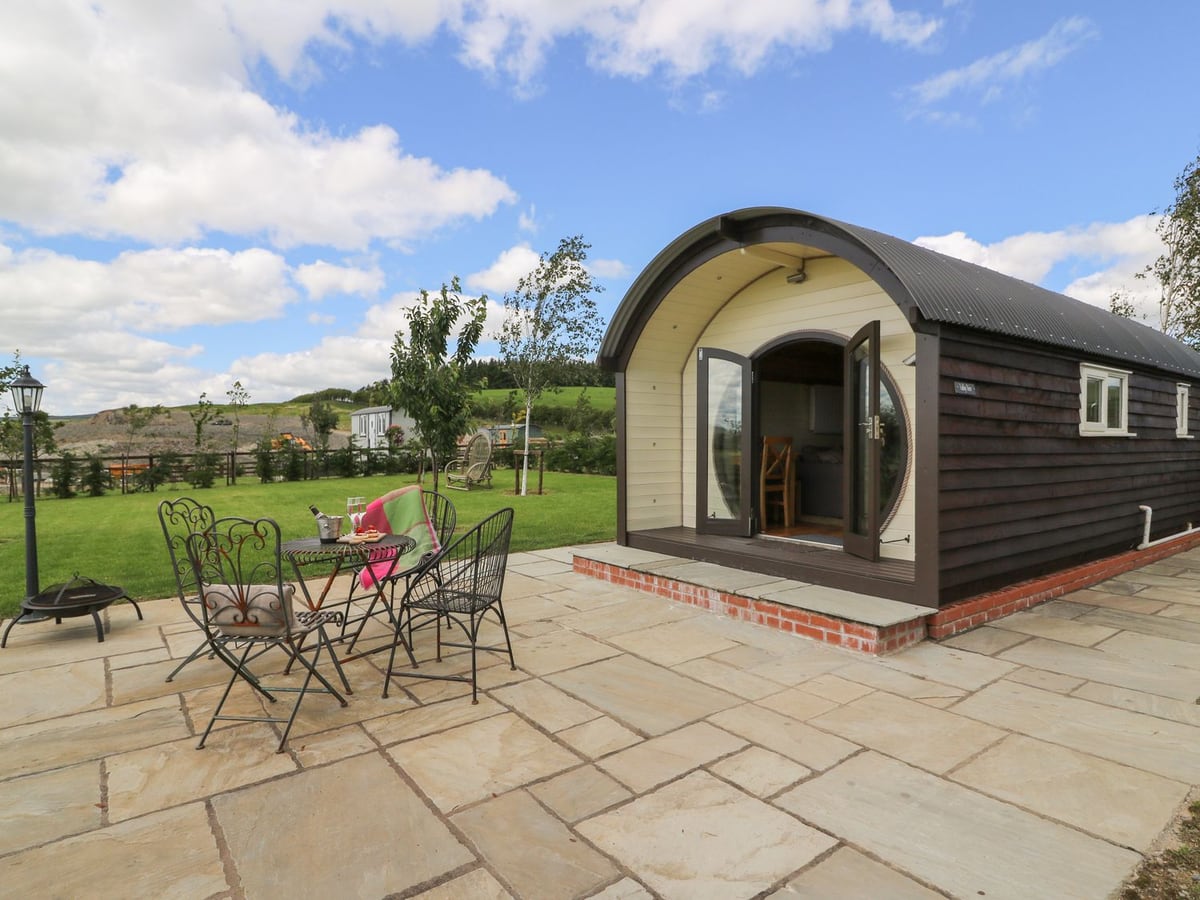 Valley View arched pod with a paved patio, bistro set and fire pit beside a lawn and countryside