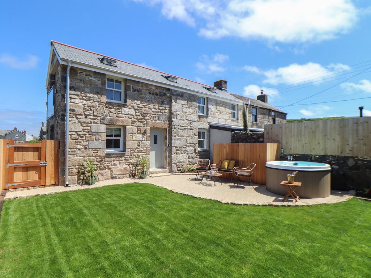 Stone exterior of Victory View with a lawn, timber gate, patio seating and round hot tub