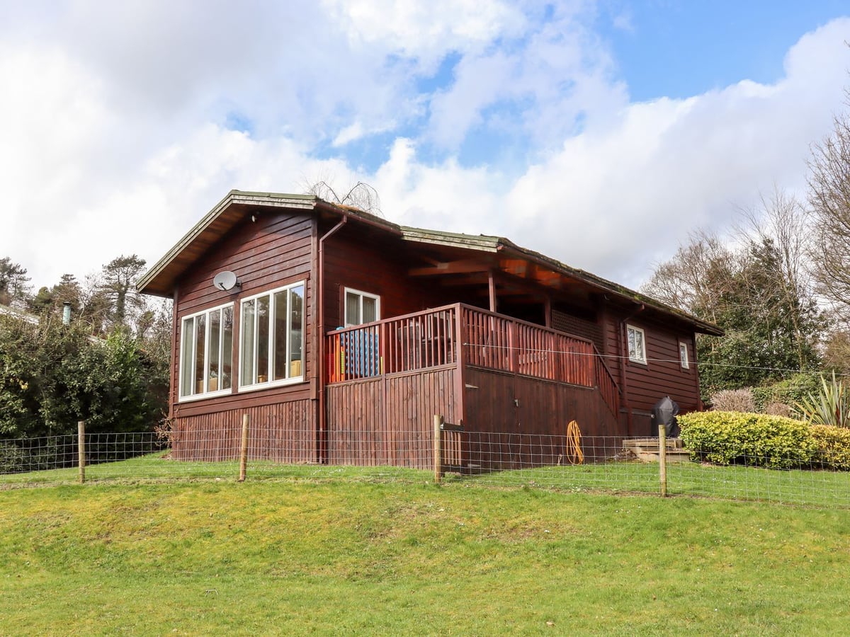 Timber exterior of Watersview Lodge with a covered veranda, lawn and trees around it.